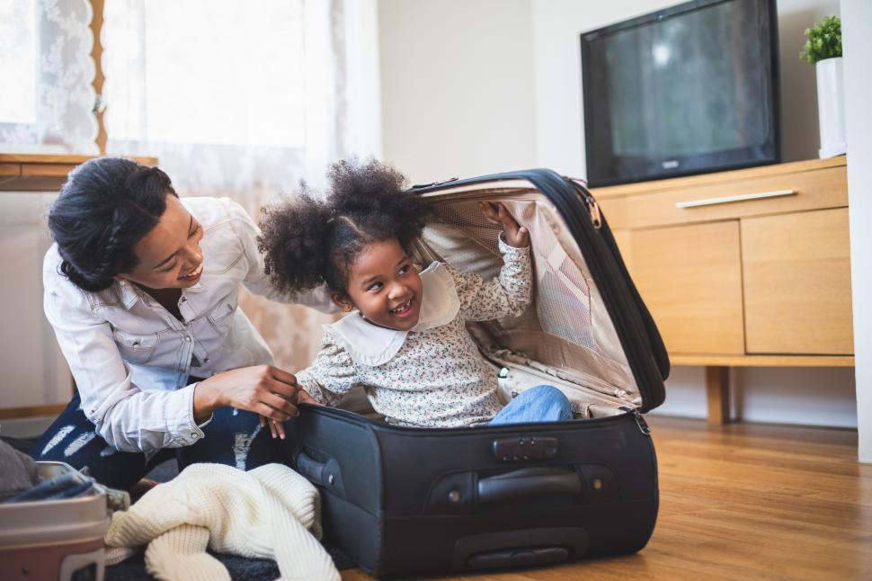 Free Image of Single mother is packing luggage - child playing in suitcase 