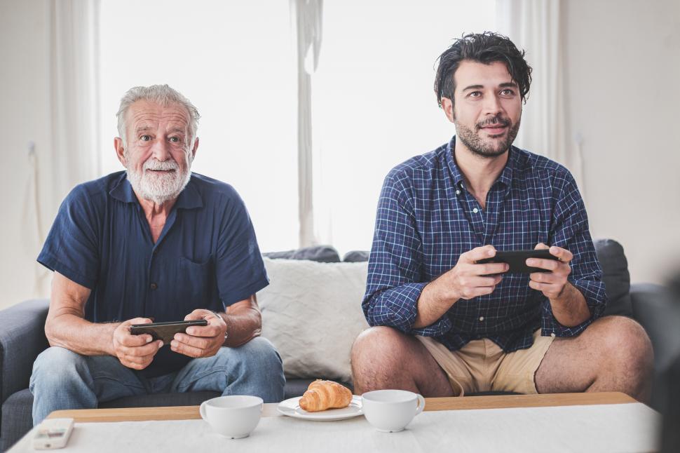 Free Image of Father and adult son fun with play online games on smartphones at home 