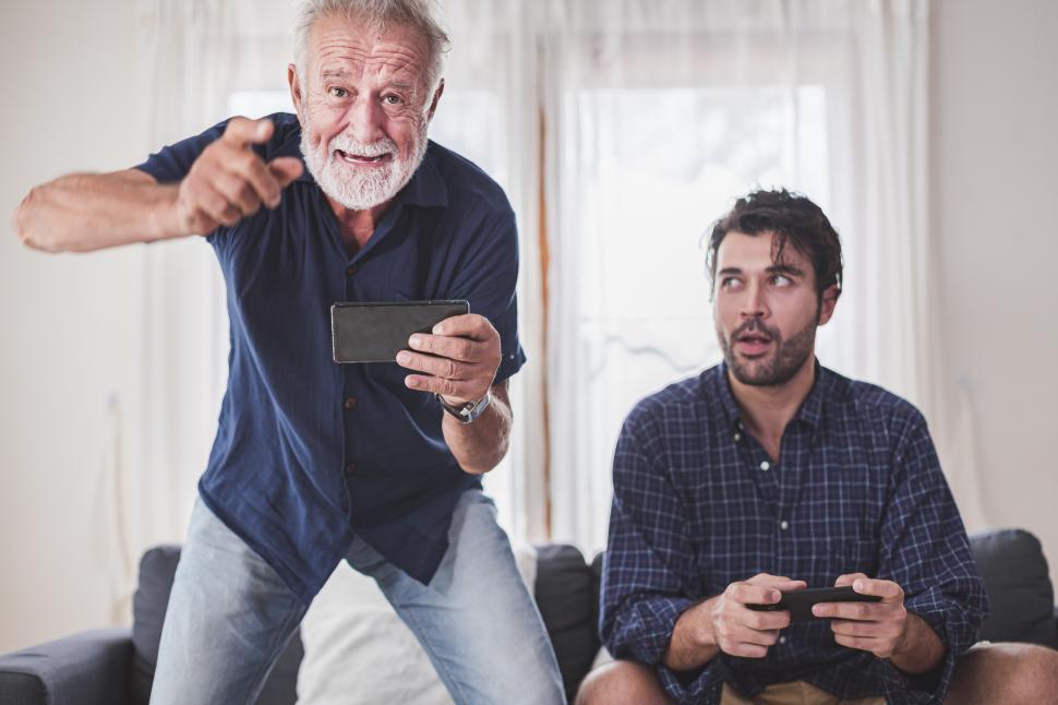 Free Image of Adult father and son enjoying competing in video game together at home 