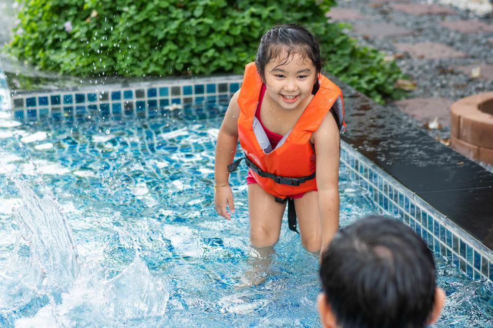 Free Image of Little kid in life saver vest playing in the swimming pool 