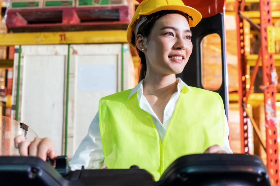 Free Image of Warehouse woman worker smile while controlling and driving 