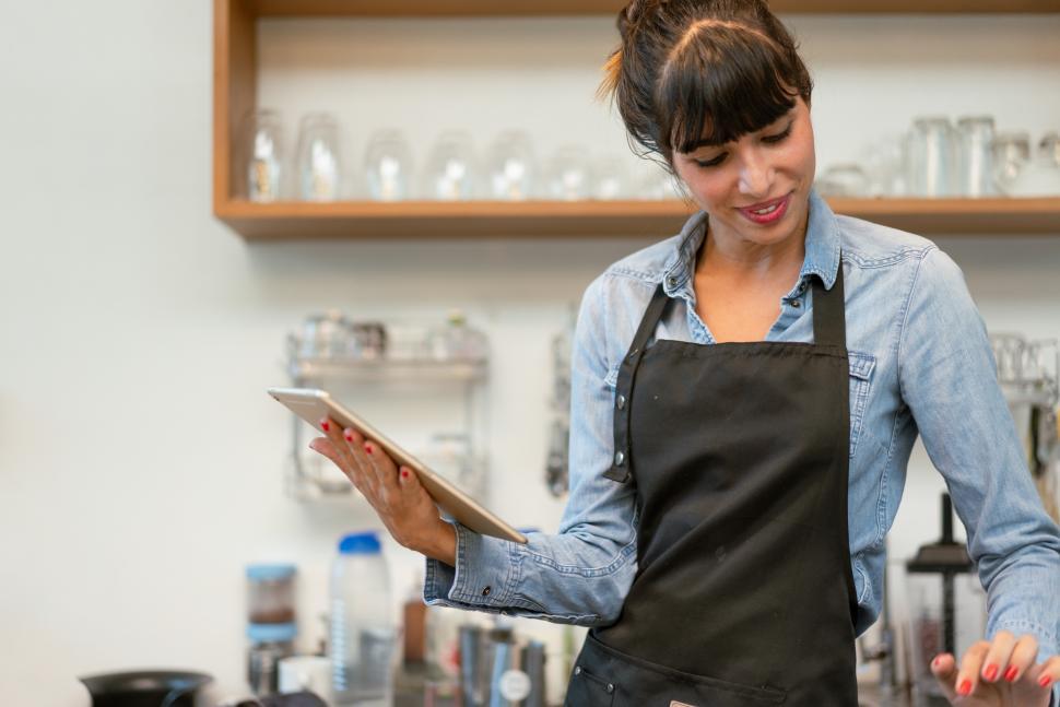 Download Free Stock Photo of Smiling female coffee shop owner using digital tablet receiving 