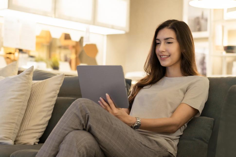 Free Image of Woman relaxing on couch playing on digital tablet 