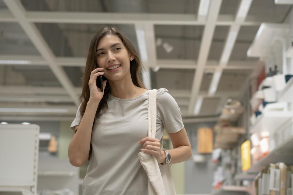 Free Image of Woman with totebag talking on the phone while shopping 