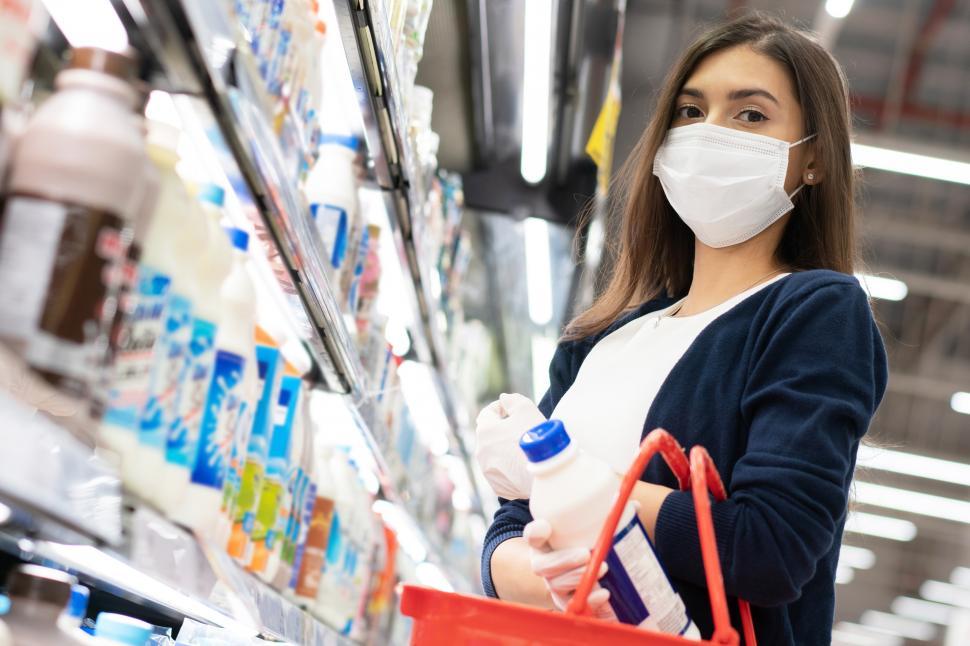 Free Image of Woman wearing medical mask and rubber glove buying groceries 