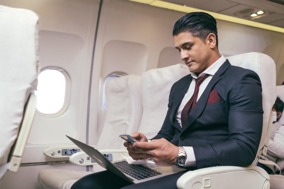 Free Image of Businessman using mobile and laptop working on airplane 