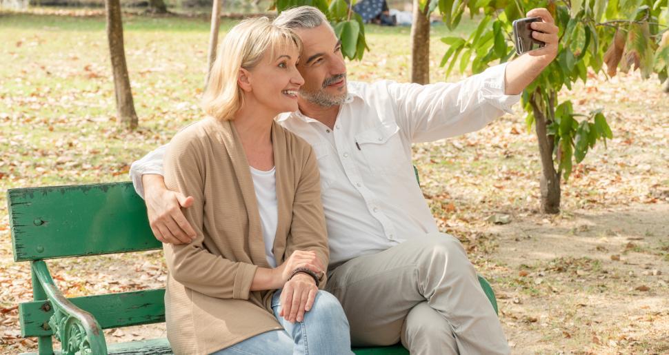 Free Image of Senior couple sitting on bench and taking selfies 