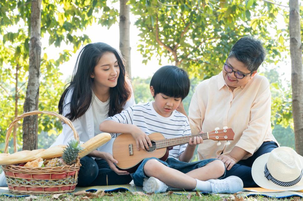 Free Image of Happy mother and grandmother watching son playing ukulele 