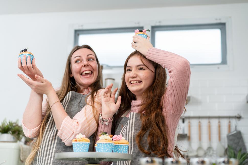 Free Image of Happy mother and daughter proud showing homemade cakes 