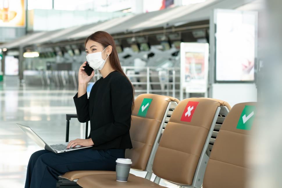 Free Image of Business woman wearing mask talking on the phone at the airpost 