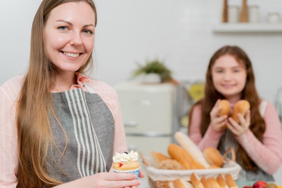 Free Image of Portrait of smiling mother showing cupcake in at kitchen 