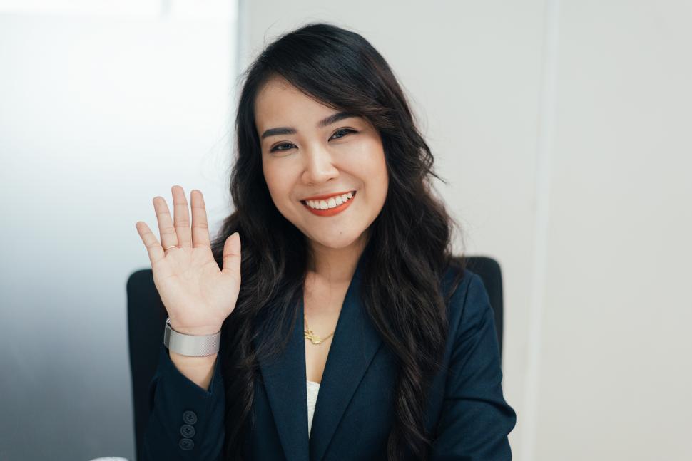 Free Image of female employee waving hand to camera greeting to customers 
