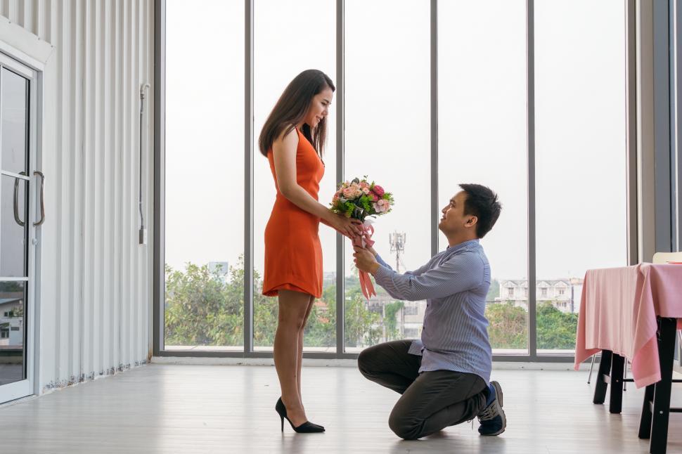 Free Image of Man kneeling on one knee giving flowers, proposing 