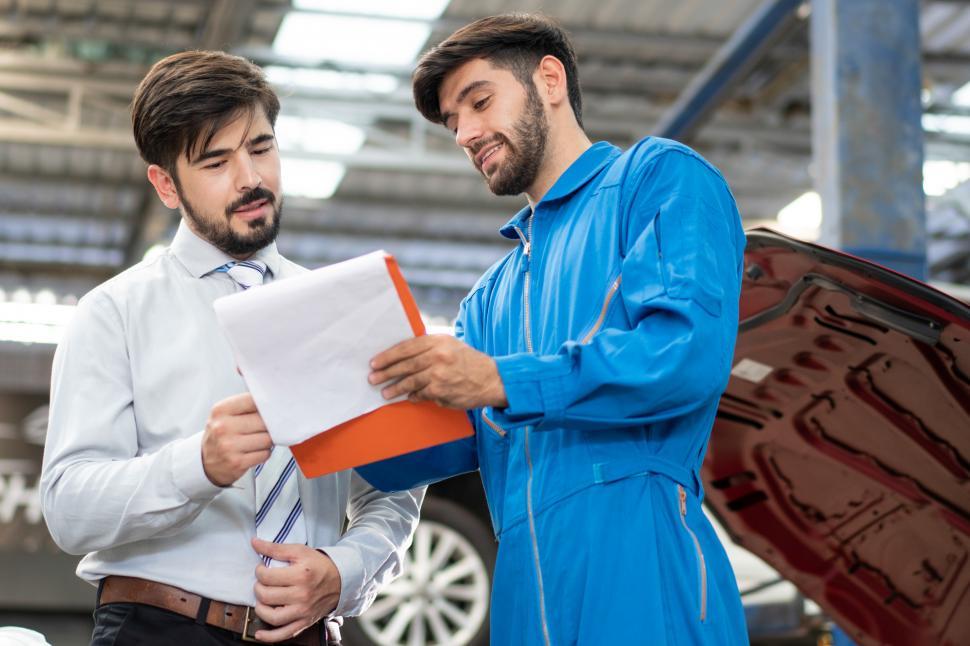 Free Image of Male mechanic showing  repair checklist to male customer 