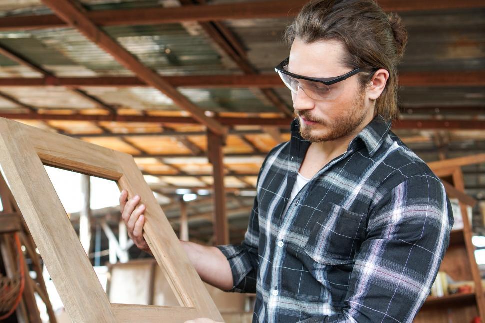 Download Free Stock Photo of Caucasian male carpenter showing wooden frame 