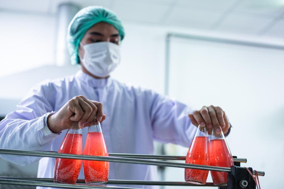 Free Image of Worker putting juice bottle into bottling production line 