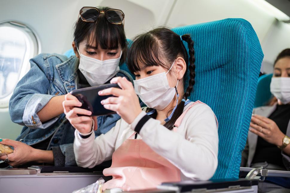 Free Image of Mother and daughter wearing mask with child on plane 