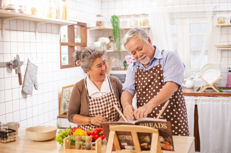 Download Free Stock Photo of Happy senior couple making salad in kitchen at home 