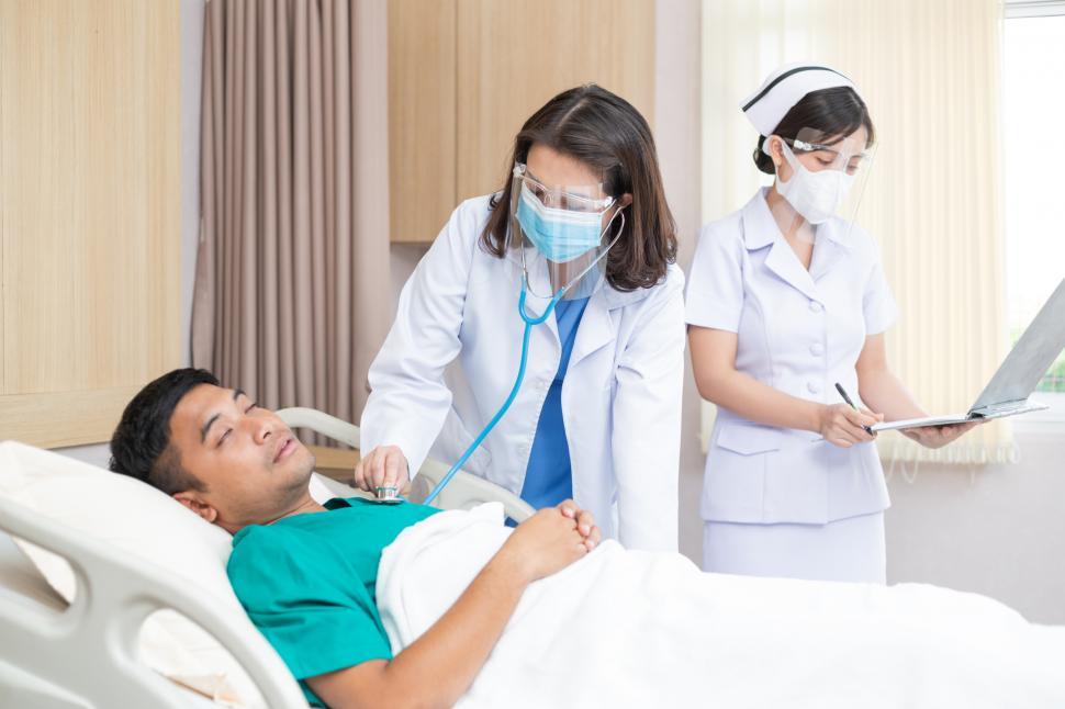 Free Image of Doctor wearing mask using stethoscope checking patient 