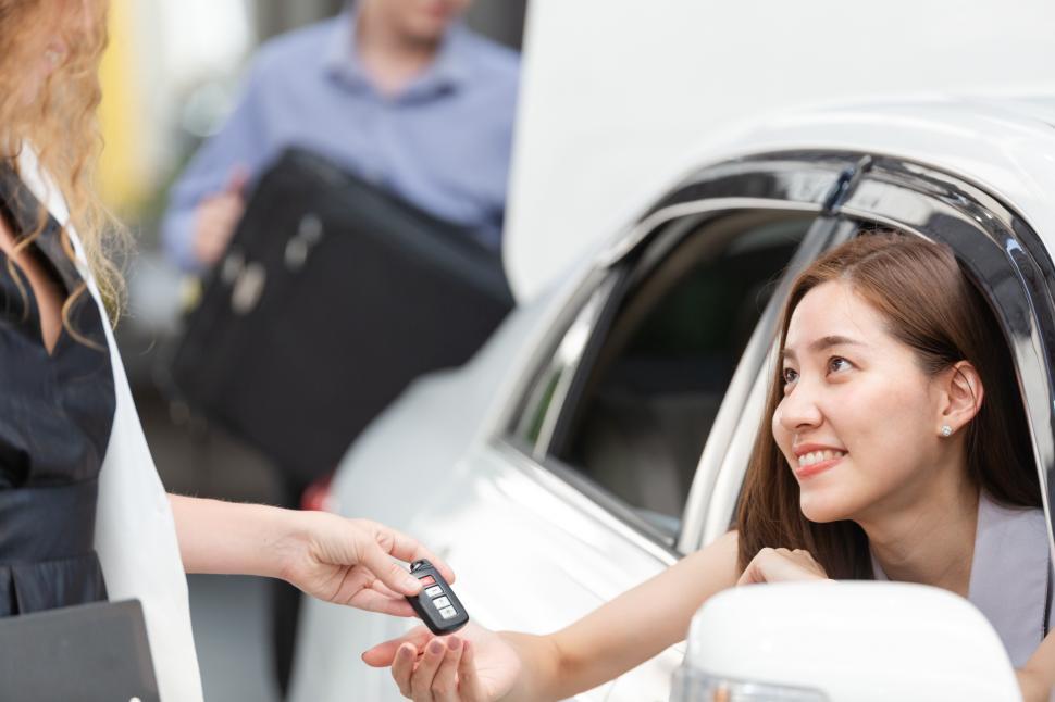 Free Image of Smiling woman customer receiving remote key from dealership 