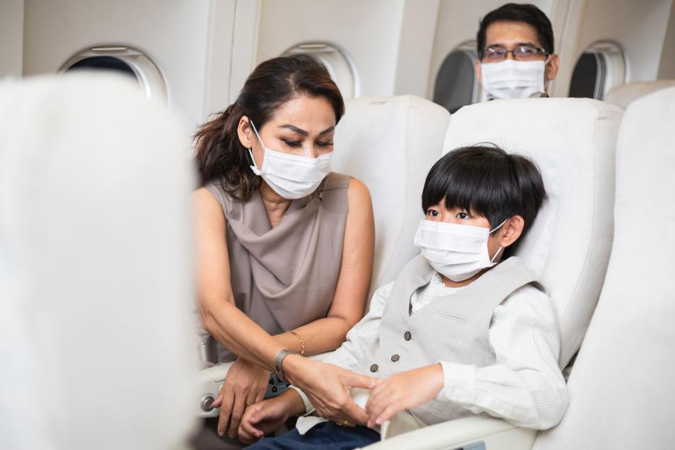 Free Image of Mother helping son to fasten seat belt on airplane 