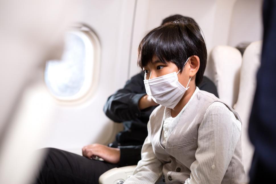 Free Image of Boy wearing protective face mask sitting on seat in airplane 