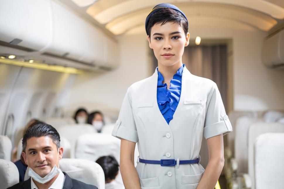 Download Free Stock Photo of Portrait of female cabin crew looking at camera on airplane 
