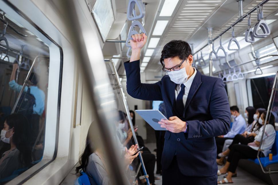 Free Image of Businessman wearing mask using digital tablet on a subway 
