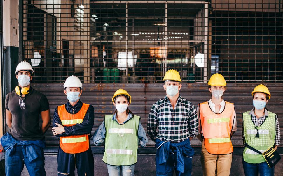 Free Image of Group of industrial workers standing in front of closed gate 