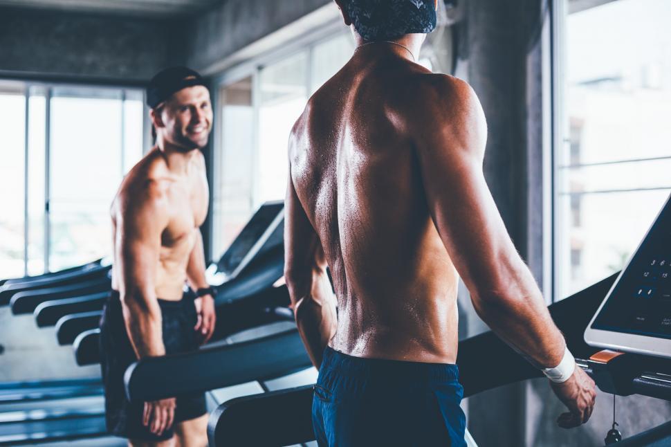 Free Image of Athletic men talking together during walking on treadmill 