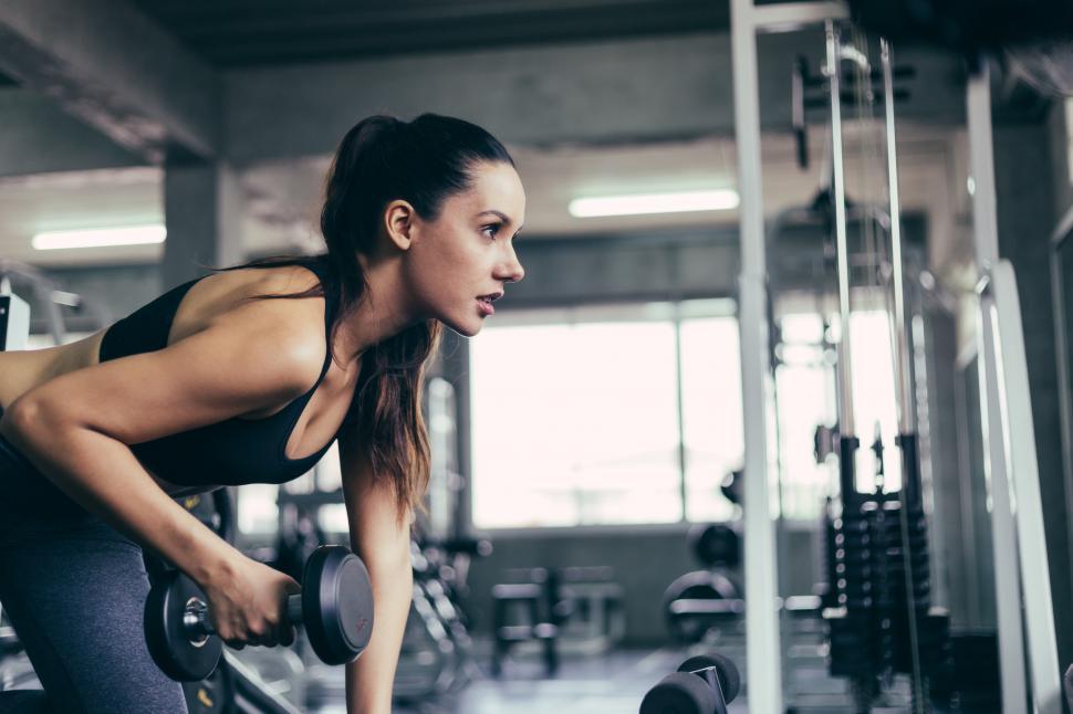 Download Free Stock Photo of Caucasian fitness woman lifting dumbbell at gym 