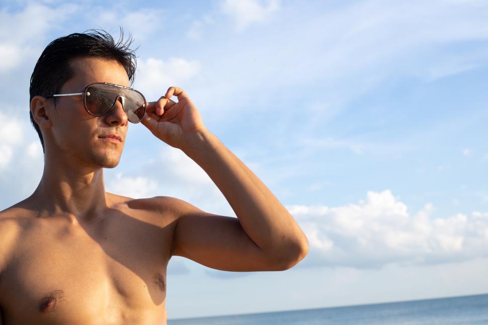 Download Free Stock Photo of Shirtless man wearing sunglasses standing at the beach 