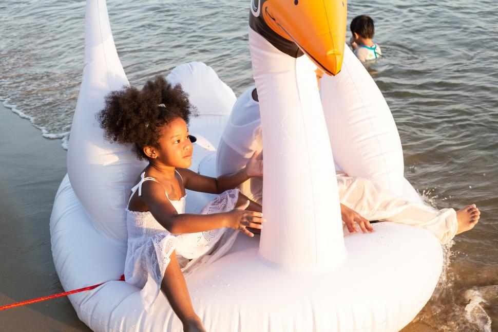 Free Image of Girl playing on inflatable goose at the beach 