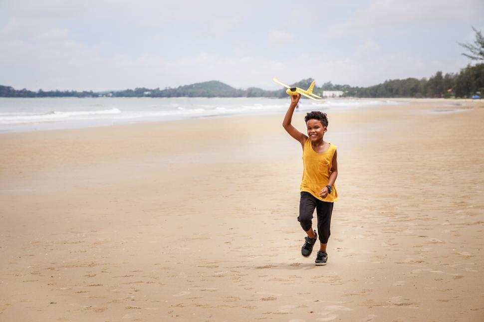 Free Image of Happy boy playing with a toy on the beach 