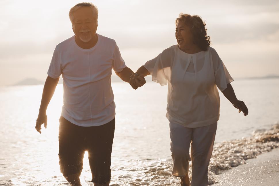 Free Image of The romantic senior couple hand in hand on beach at sunset 