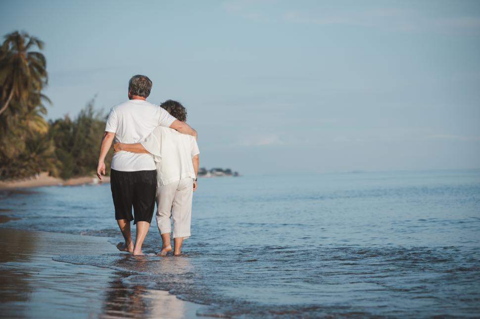 Free Image of Couple walk together in the shallow tide 