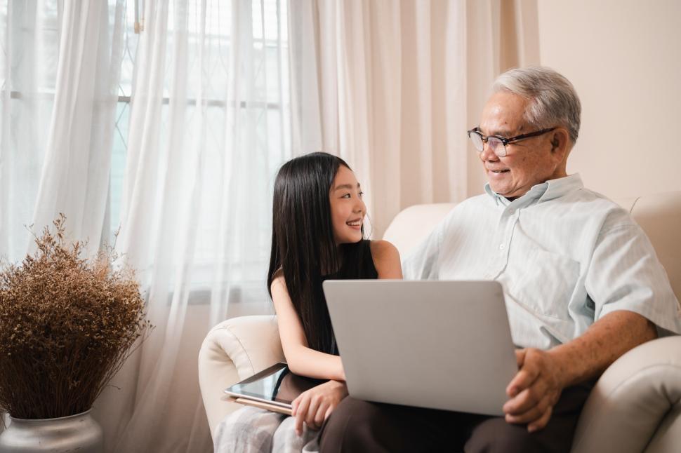Download Free Stock Photo of Happy retired grandfather and pretty granddaughter watch laptop together 