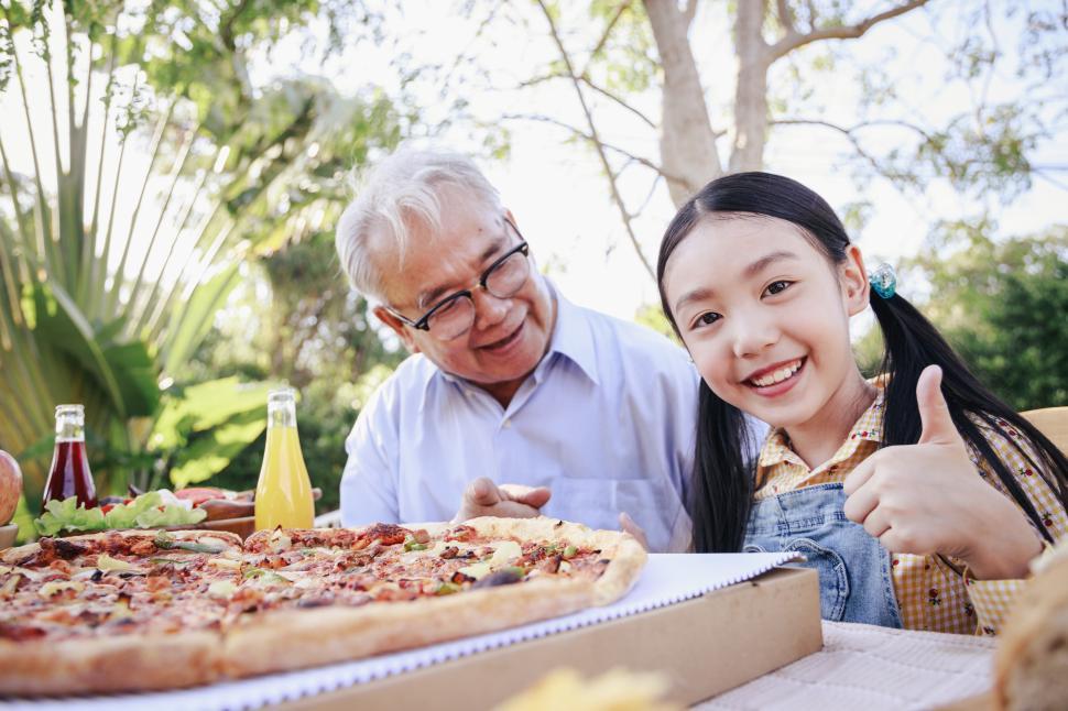 Free Image of Grandfather and granddaughter eating pizza together outdoors 