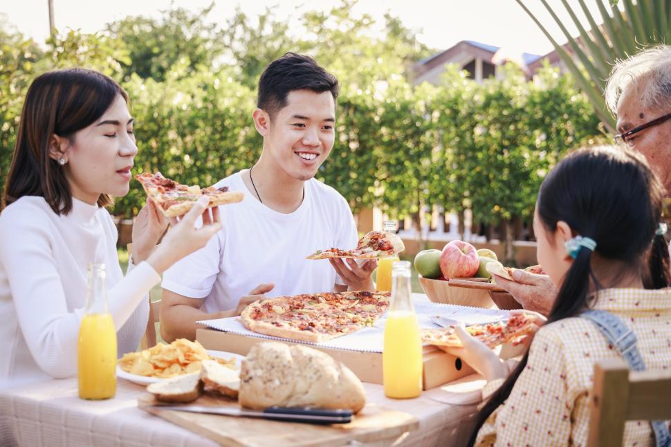 Free Image of Happy asian family having enjoying mealpizaa, salad,snack, oran 