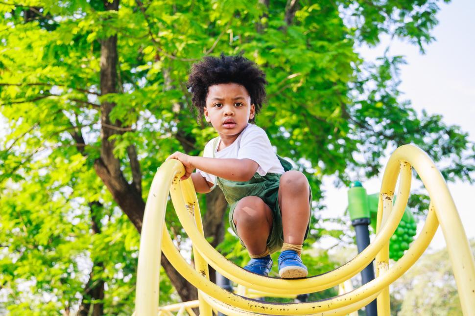 Free Image of Cute little kid looking at the camera from a climbing structure 