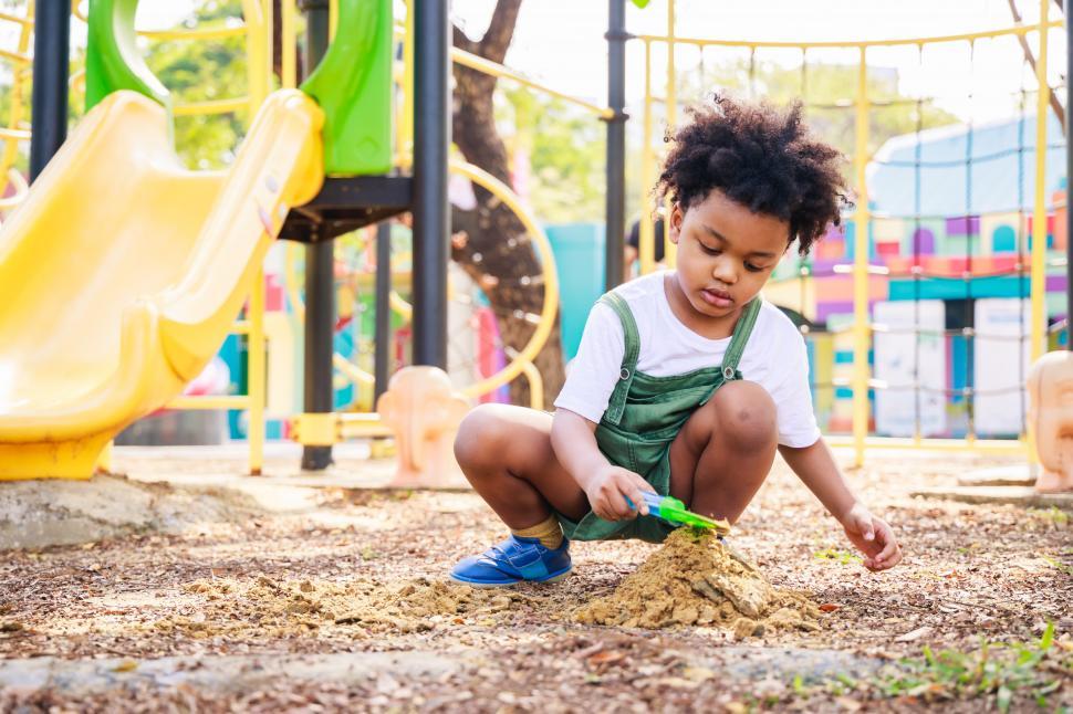 Free Image of Young boy digging in playground dirt 