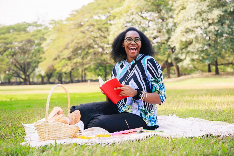 Free Image of Happy woman reading a book in the park 