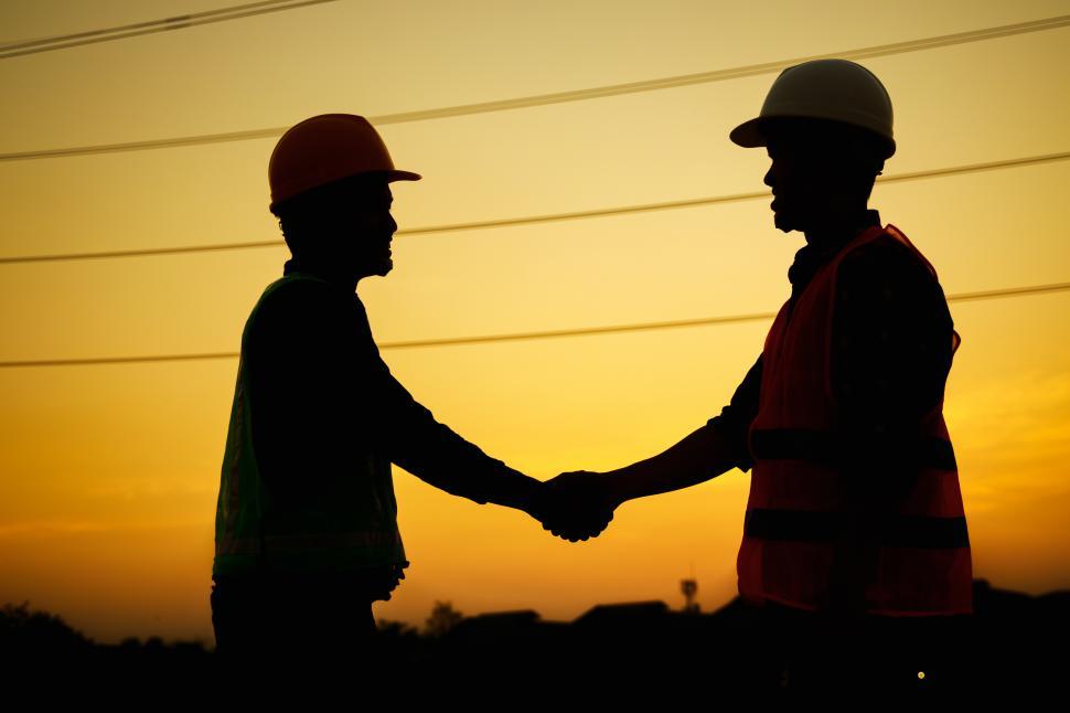 Download Free Stock Photo of Silhouette of Engineer and foreman shaking hands at construction site 