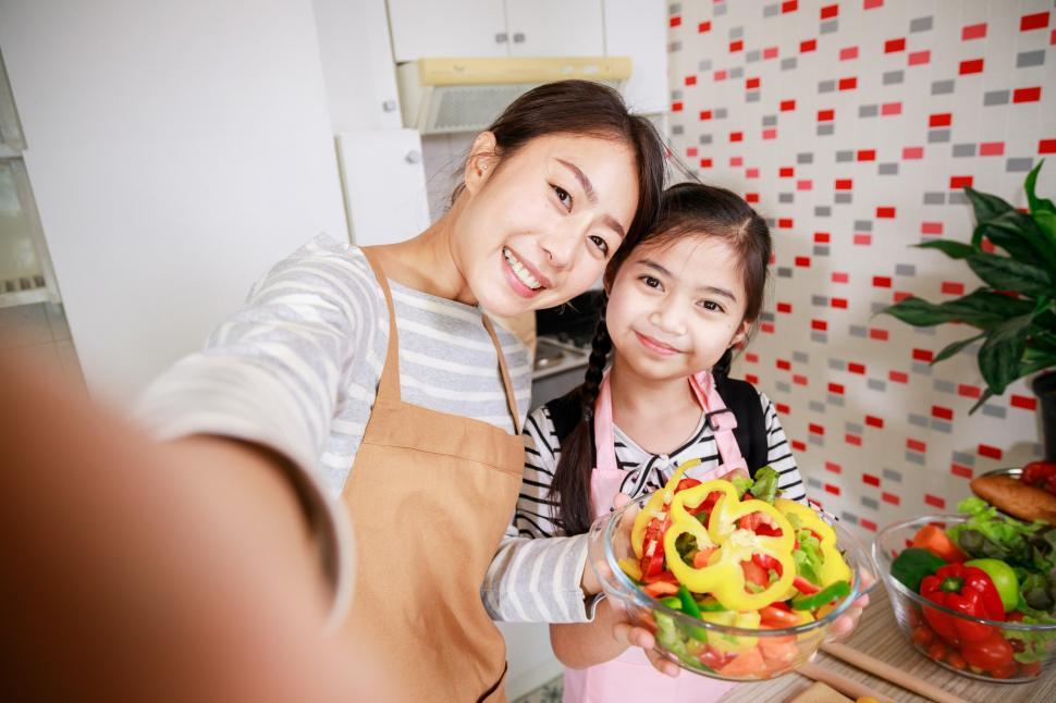 Free Image of Mother and daughter preparing salad and taking a selfie 