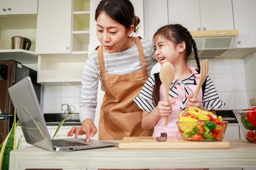 Free Image of Mother and daughter preparing salad and using online recipe 