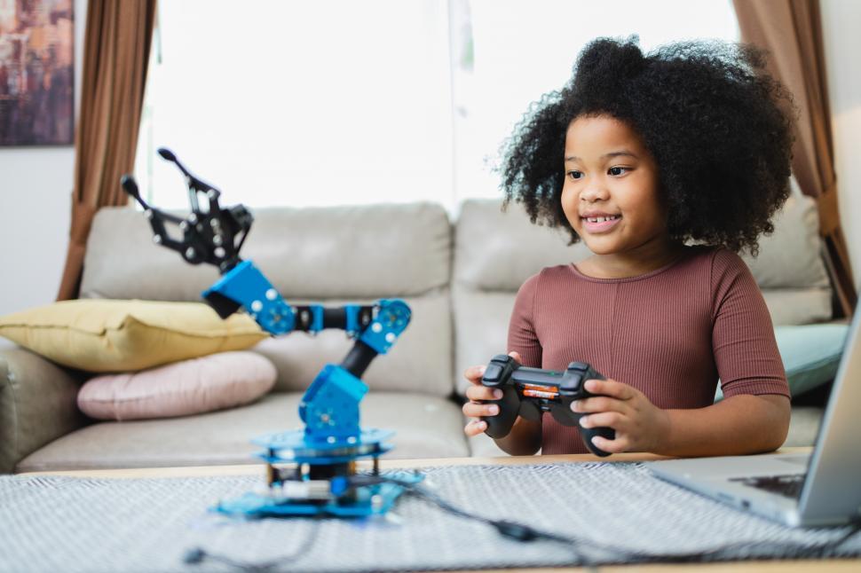 Download Free Stock Photo of Enthusiastic young STEM girl controls robot arm 