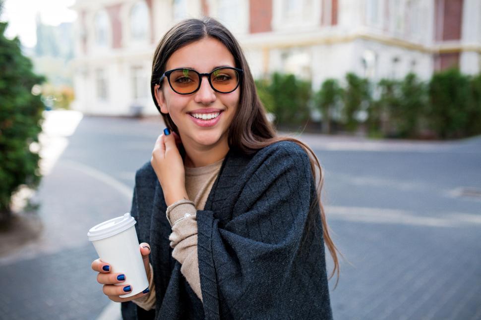 Free Image of Smiling shy woman walking with coffee on the street 