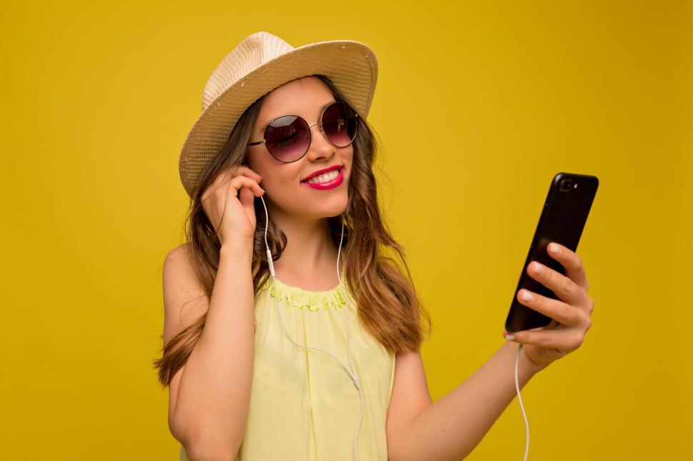 Free Image of Smiling happy woman in summer hat and sunglasses with smartphone 