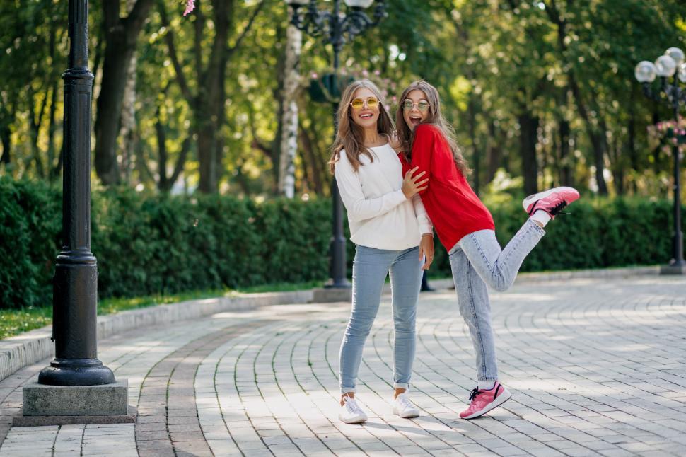 Download Free Stock Photo of Full-lenght outdoor portrait of two friendly happy girls in public park 
