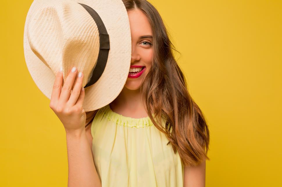 Free Image of Portrait of pretty woman holding a hat over one eye 